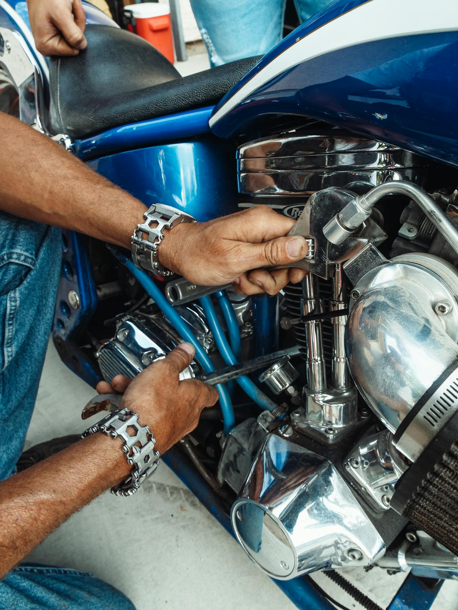 A close-up of a mechanic working on a motorcycle engine using tools.